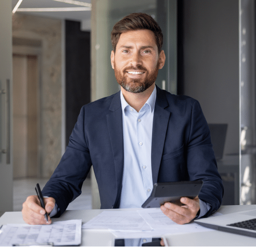 a man sitting at a desk holding a pen